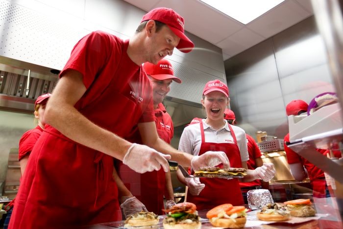 équipe préparant des burgers premium dans un restaurant Five Guys